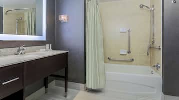 Een moderne badkamer met een gebogen douche, een wastafel met spiegel en een bad.