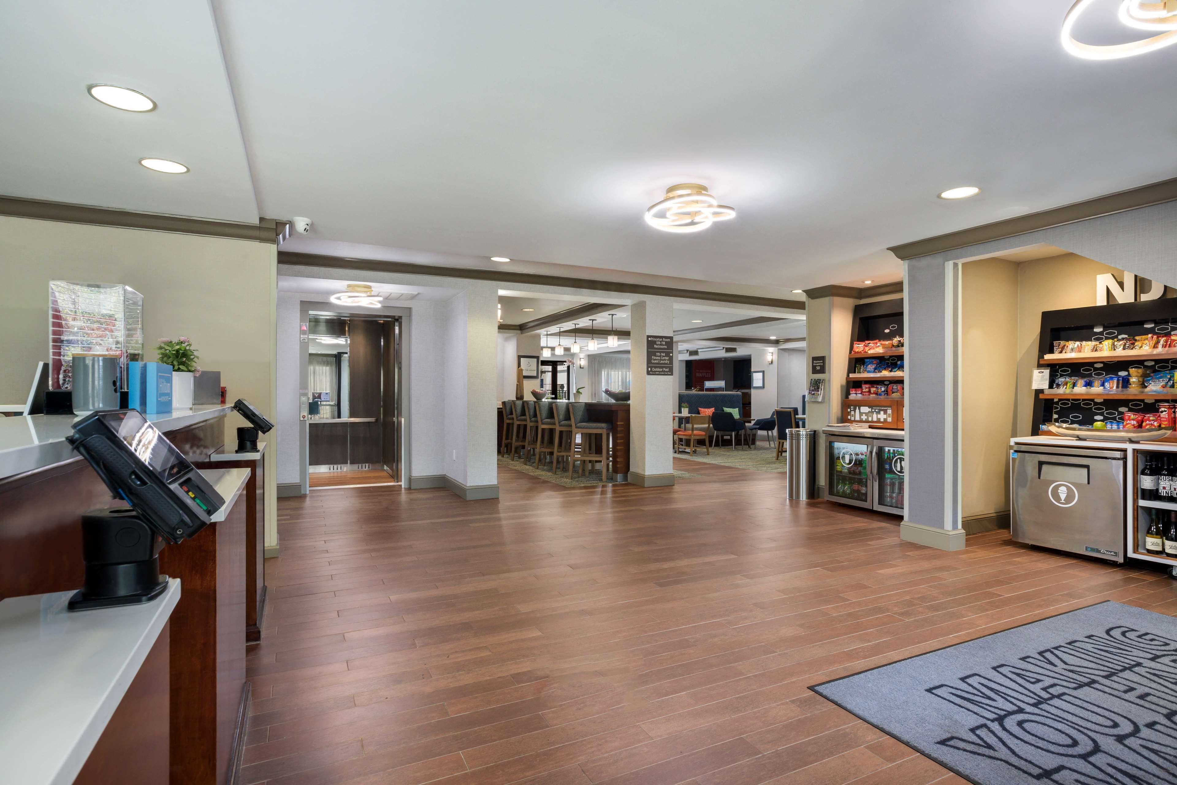 A modern hotel lobby with a reception desk, a bar area, and a kitchenette.
