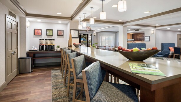 A modern kitchen with a long island, bar stools, and a bowl of fruit. - Hampton Inn Princeton (Princeton)