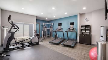 Ein modernes Fitnessstudio mit Laufbändern, Crosstrainern und verschiedenen Trainingsgeräten.
