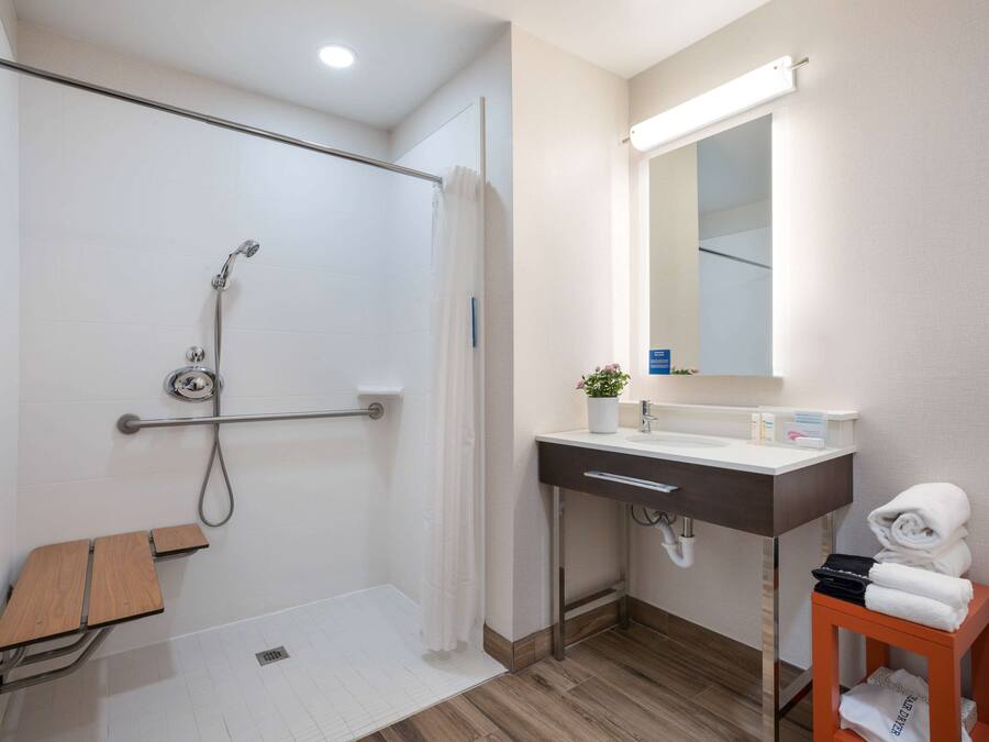 Un baño moderno con ducha, lavabo, espejo y toallero.