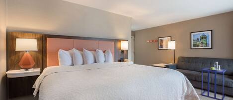 A hotel room with a large bed, a sofa, and a small table.