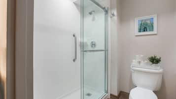 Ein modernes Badezimmer mit einer Duschkabine, einer weißen Toilette und einem gerahmten Bild an der Wand.
