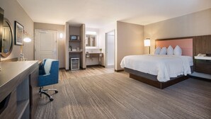 A hotel room with a bed, desk, chair, and a small kitchenette. - Hampton Inn Princeton (Princeton)