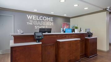 A reception desk with a "Welcome to the Garden State" sign, a digital kiosk, and a Hilton sign.