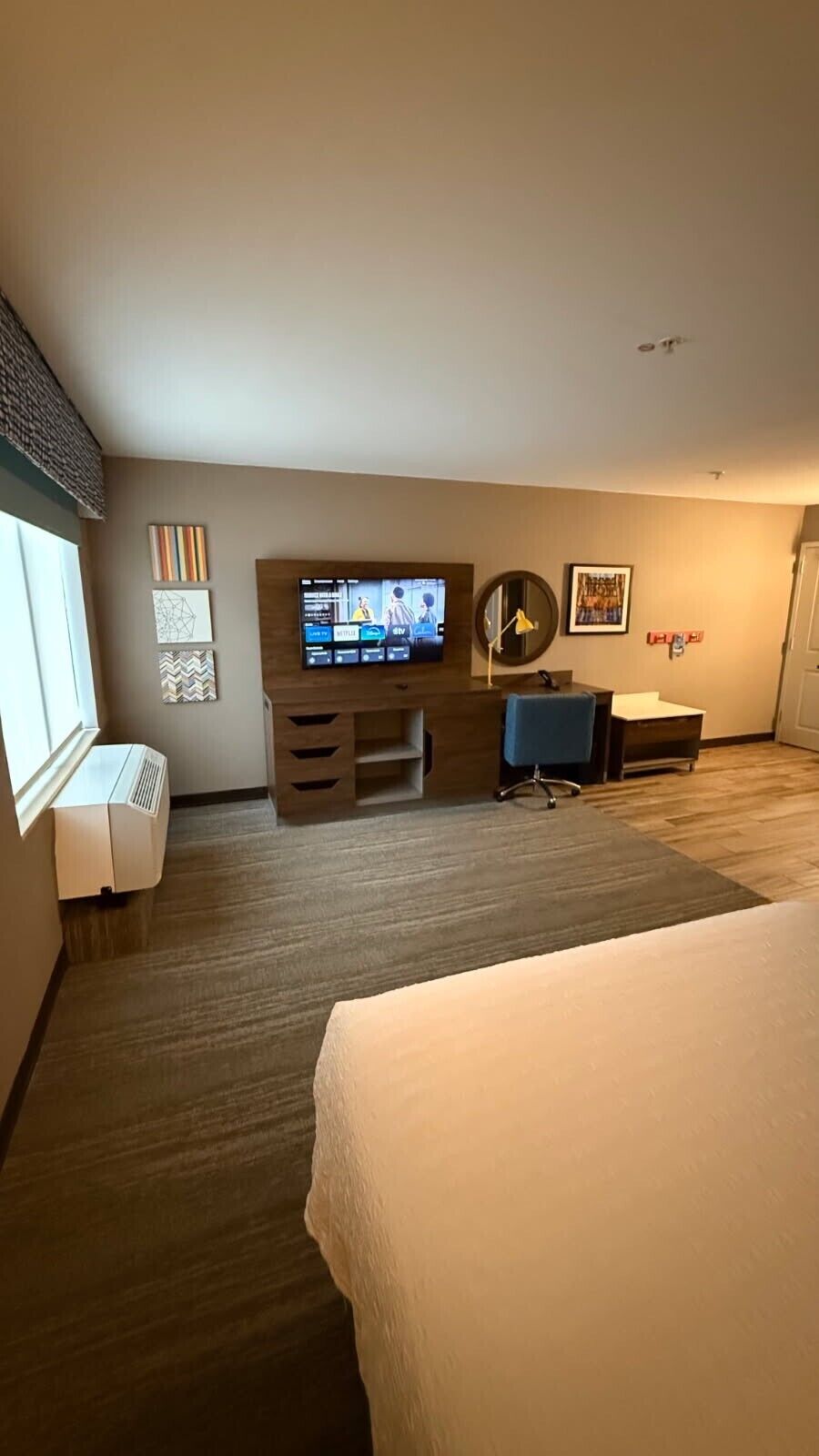 A hotel room with a bed, a desk, a TV, and a window.