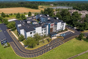 A modern hotel with a central building and a parking lot.