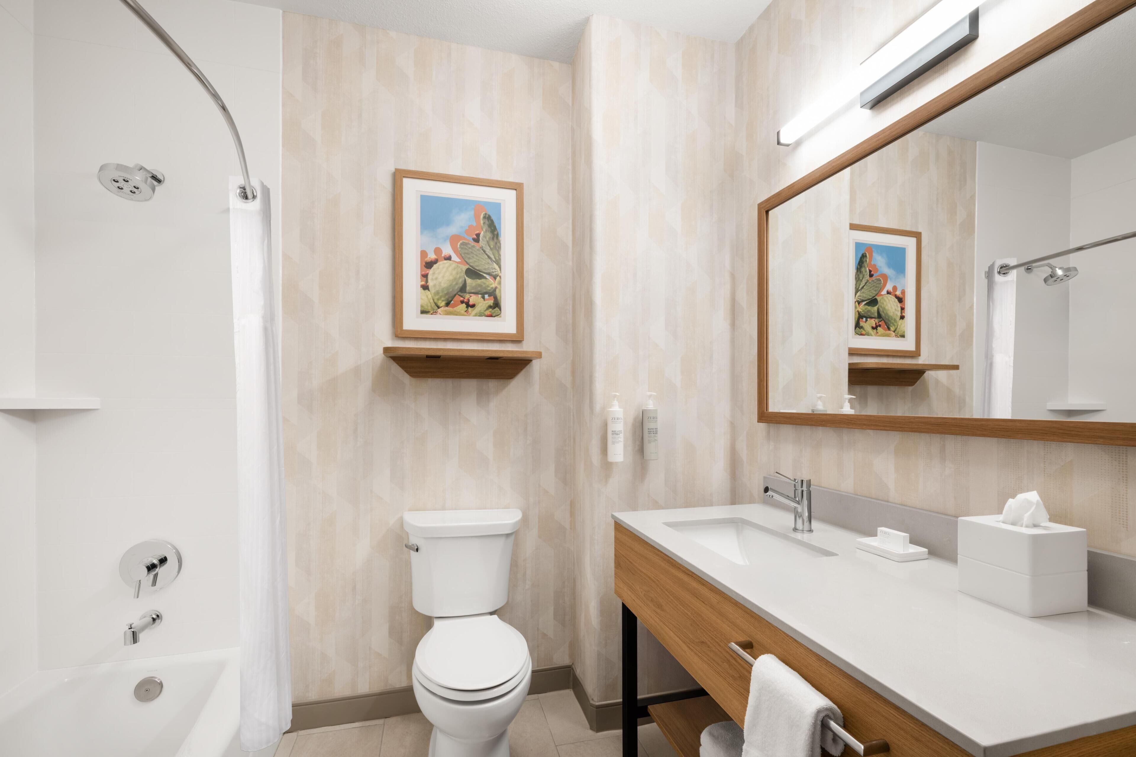 A modern bathroom with a shower, toilet, sink, and a mirror.