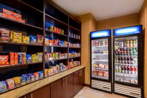Un espace dédié aux collations et aux boissons, avec des étagères remplies de divers en-cas et un réfrigérateur portant l’inscription « aliments surgelés ».