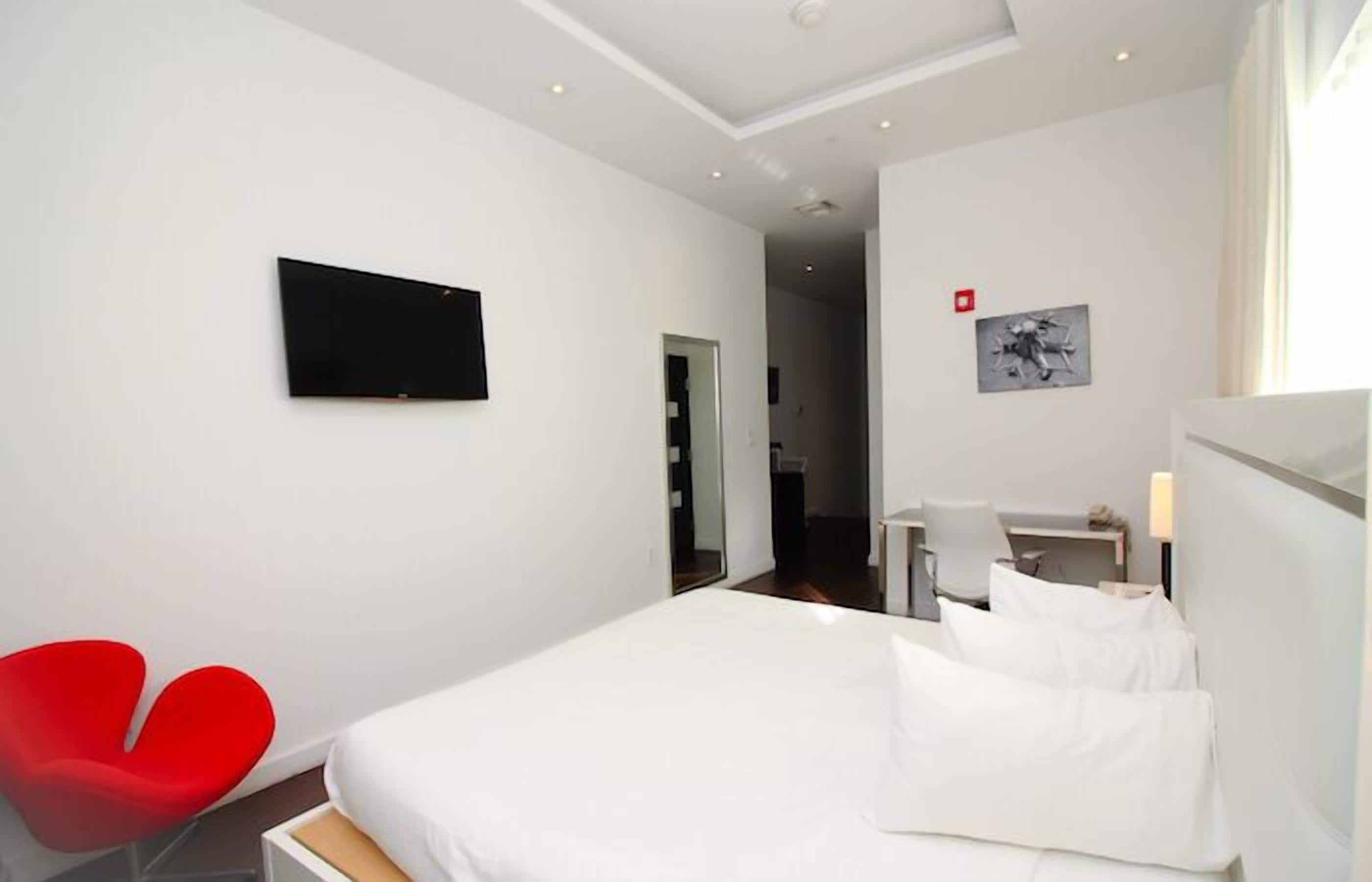 A hotel room with a bed, a desk, a chair, and a TV on the wall.