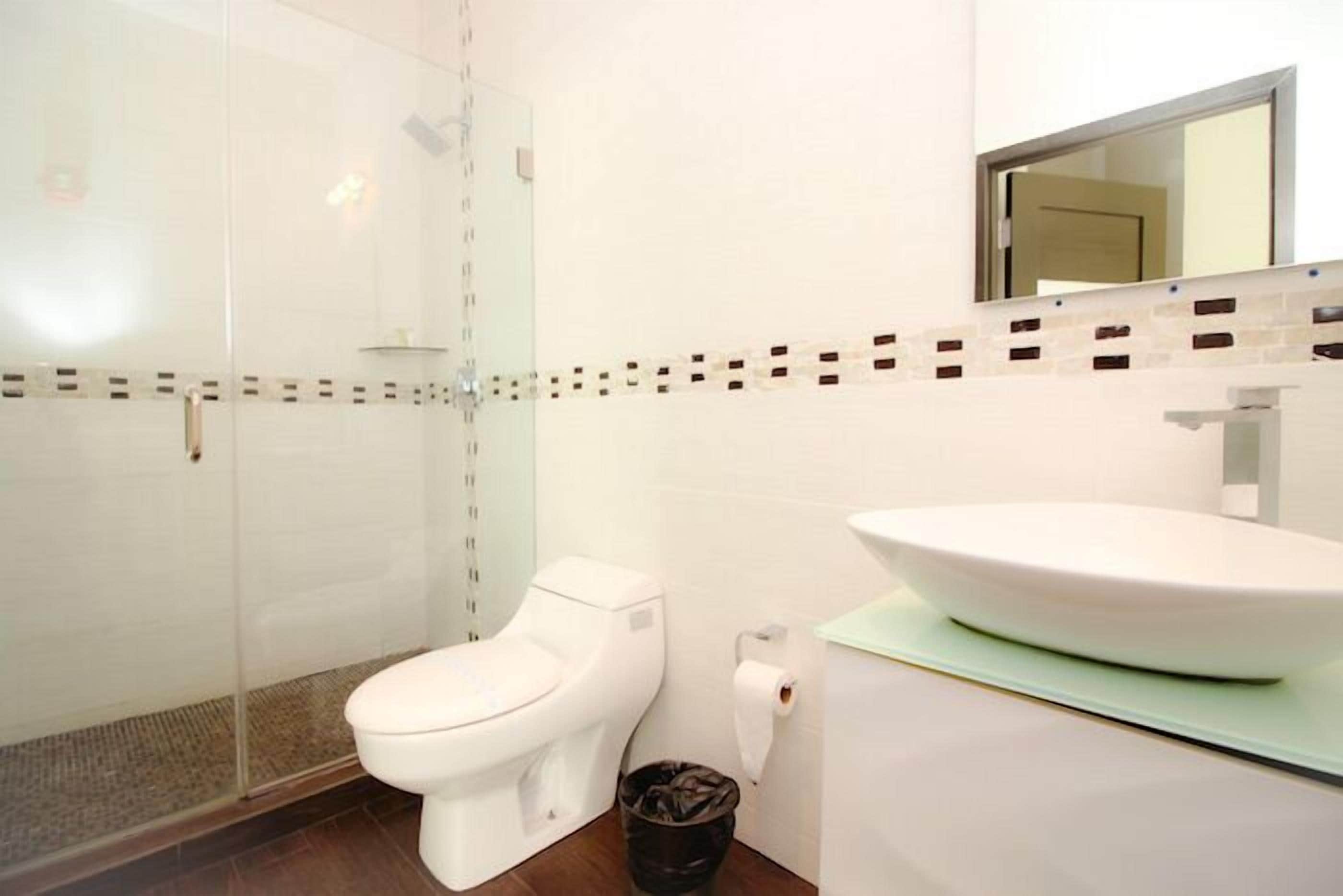 Ein Badezimmer mit einer Duschkabine, einer Toilette und einem Waschbecken mit Spiegel.