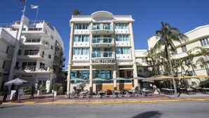 A multi-story hotel with balconies, outdoor seating, and palm trees.