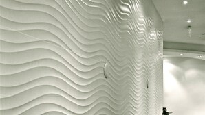A textured wall with a wavy pattern, a carpeted floor, and recessed lighting.