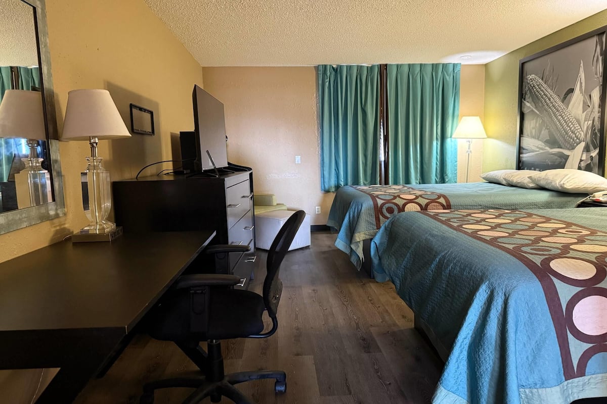 Une chambre d’hôtel équipée d’un bureau, d’une chaise, d’un lit et de rideaux.