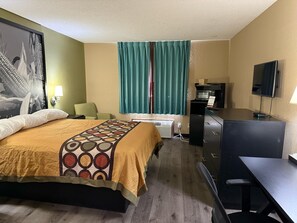 Une chambre d’hôtel équipée d’un lit, d’un bureau, d’une chaise, d’une télévision, d’un four à micro-ondes et d’un petit réfrigérateur.
