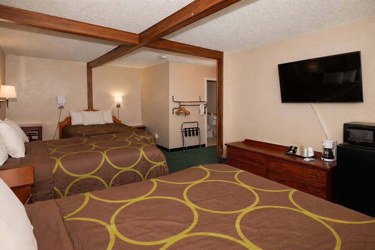 A hotel room with two beds, a TV, a dresser, and a mirror.