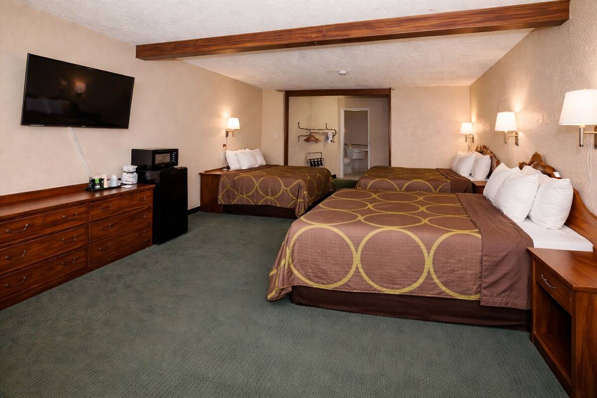 A hotel room with two beds, a TV, a desk, and a microwave.