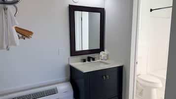 Un baño con un lavamanos blanco, armarios oscuros, un espejo y un inodoro blanco.