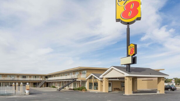 A Super 8 motel with a large sign, a parking lot, and a building with multiple balconies.