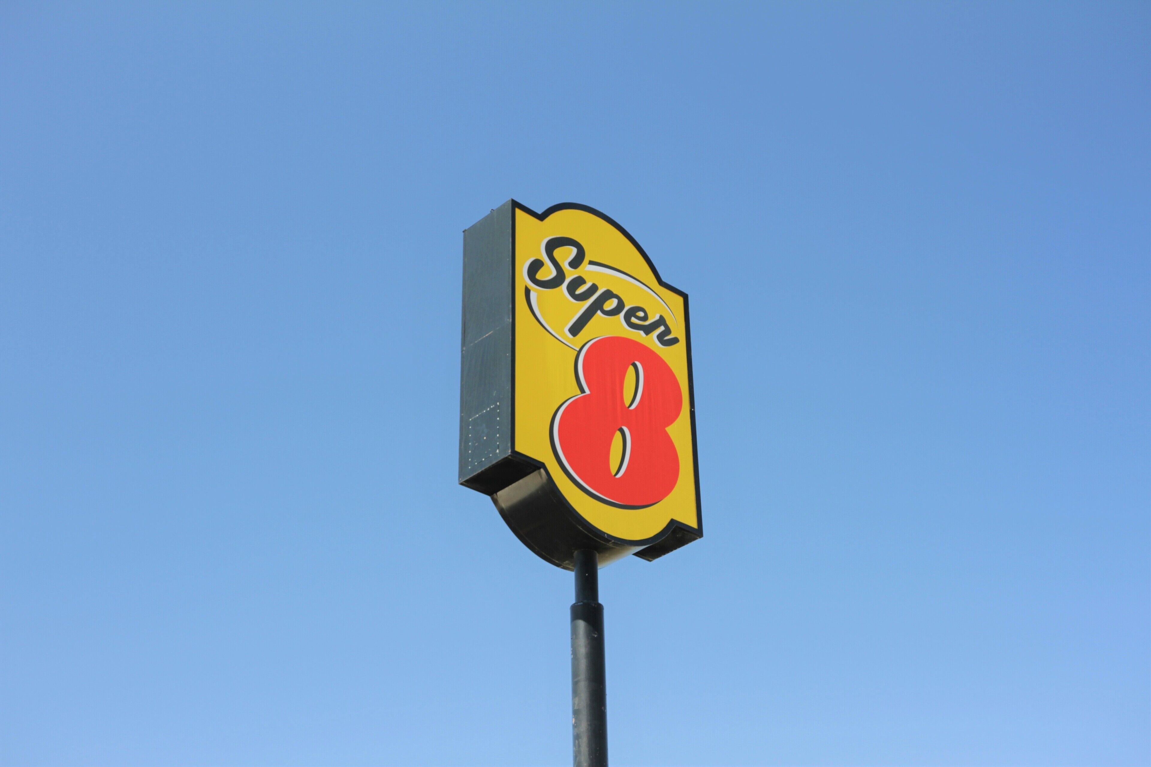 A Super 8 sign against a clear blue sky.