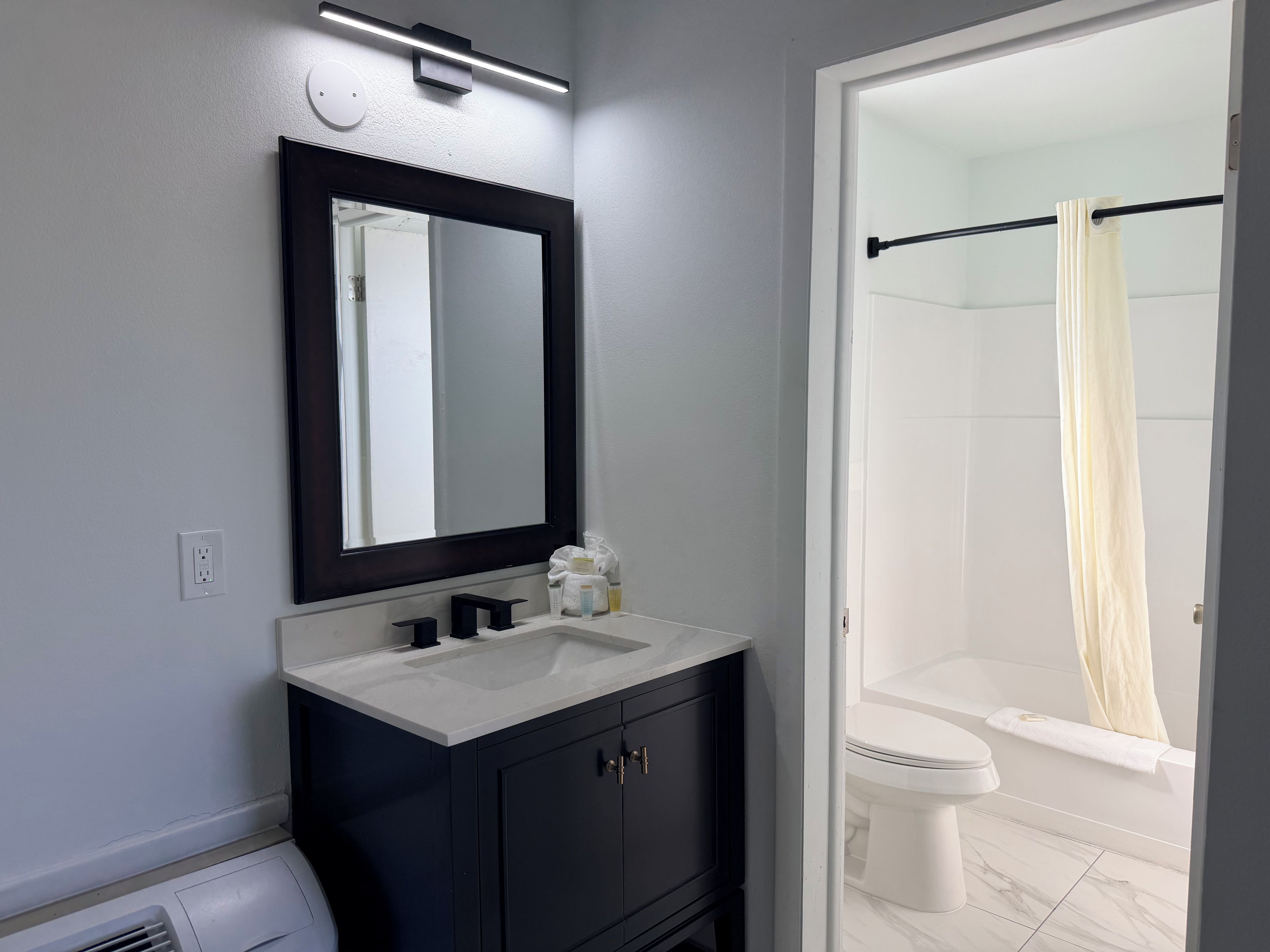 A bathroom with a dark vanity, a white sink, and a shower curtain.