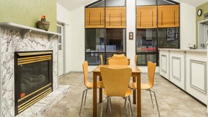 A dining area with a marble fireplace, wooden dining table, and chairs.