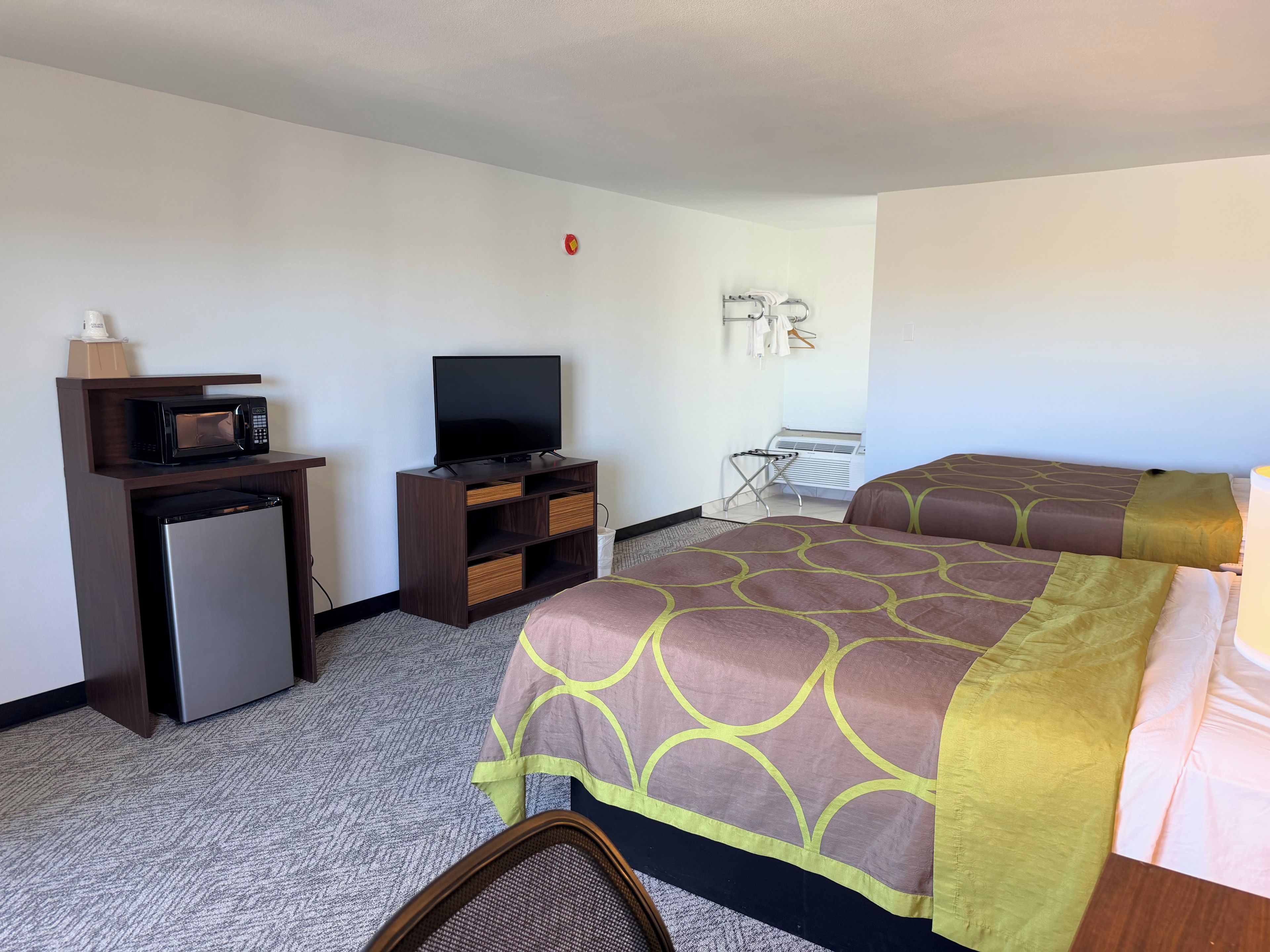 A hotel room with a bed, a TV, a mini-fridge, a microwave, and a seating area.