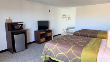 A hotel room with a bed, a TV, a mini-fridge, a microwave, and a seating area.