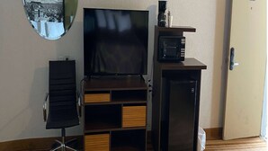 A hotel room with a flat-screen TV, a coffee maker, a microwave, and a refrigerator.
