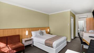 Habitación de hotel con cama, escritorio, silla, mesita de noche y sofá.