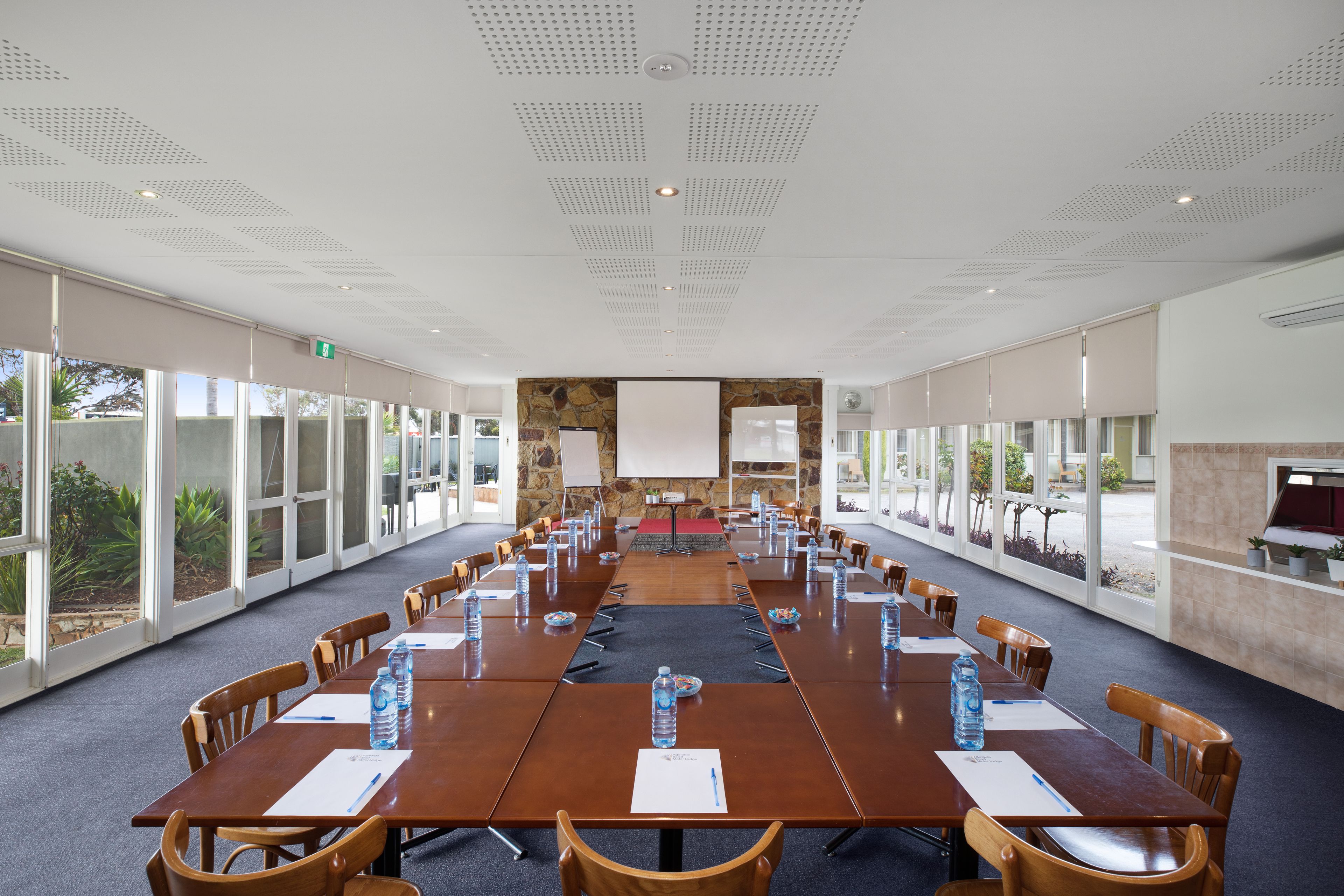 A conference room with a long table, chairs, water bottles, and a whiteboard.