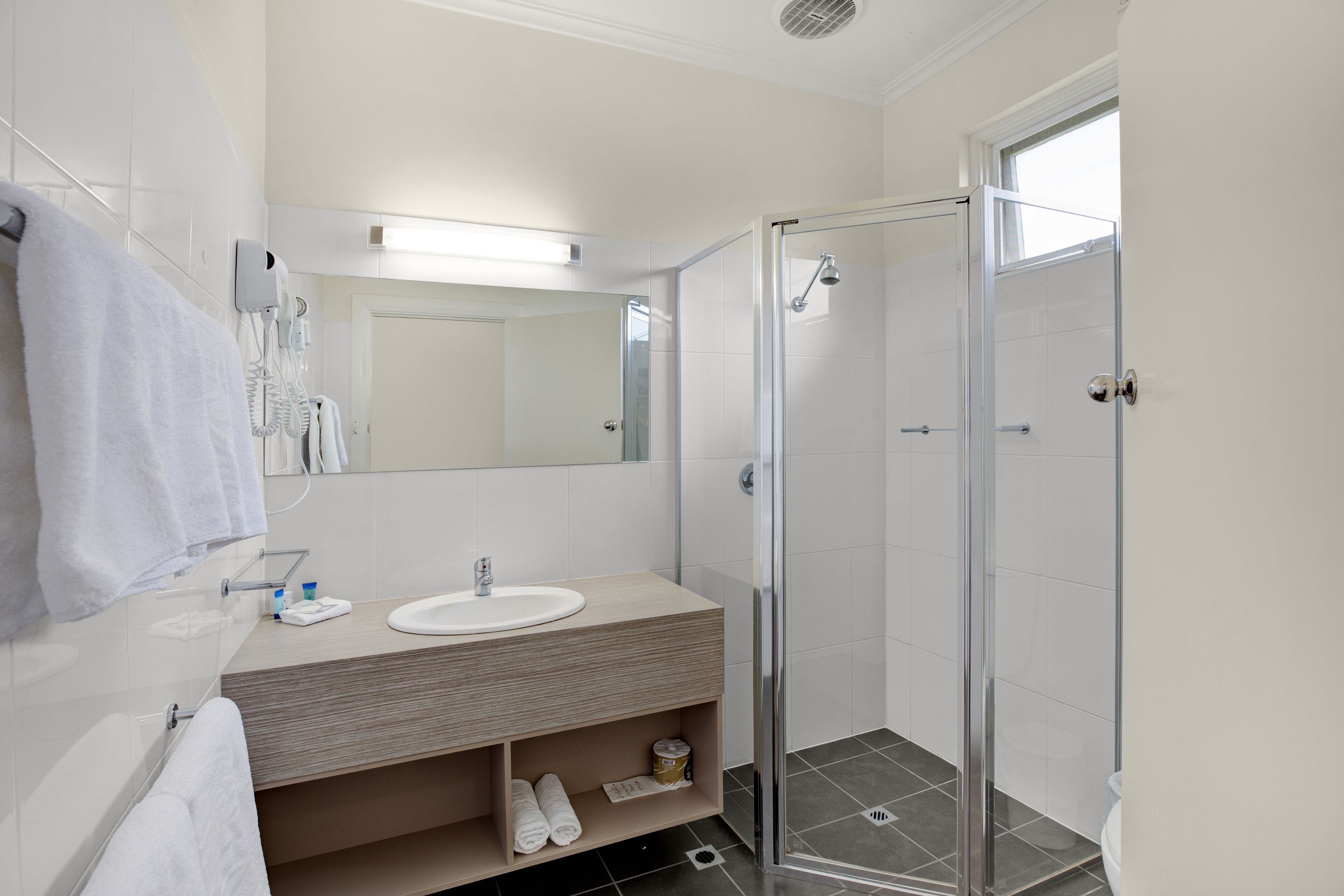 A modern bathroom with a glass-enclosed shower, a sink with a wooden vanity, and a mirror above the vanity.