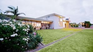 Un bâtiment moderne doté d’une pelouse bien entretenue, d’une façade en pierre et surplombant un ciel dégagé.