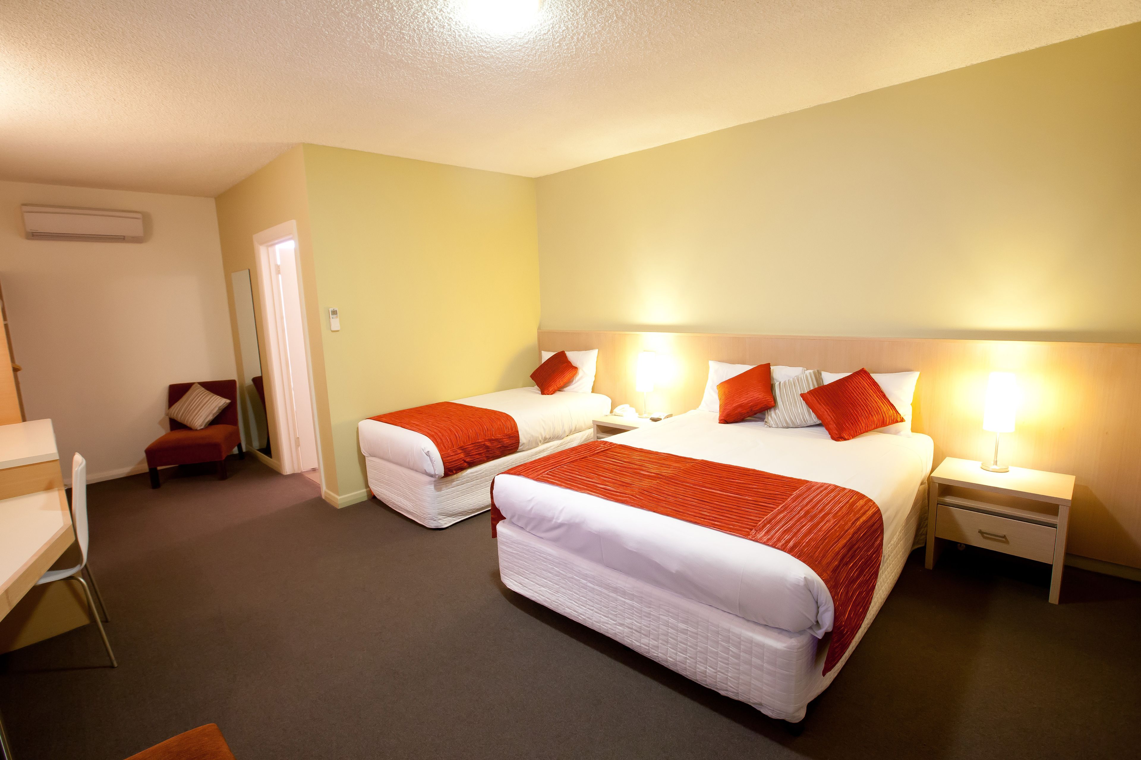 A hotel room with two beds, a desk, and a chair.
