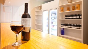 Une bouteille de vin et un verre sur un comptoir en bois, avec des étagères remplies de bouteilles de vin en arrière-plan.