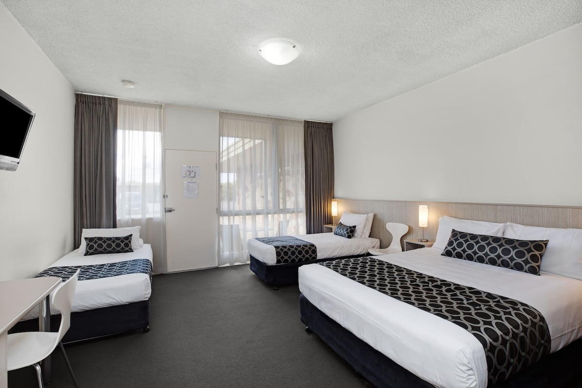 Ett hotellrum med två sängar, ett skrivbord och en stol.