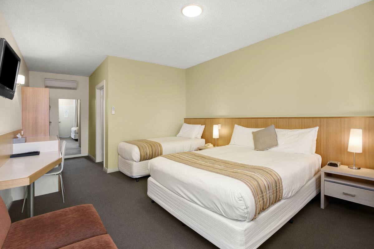Ett hotellrum med två sängar, ett skrivbord, en tv och en stol.
