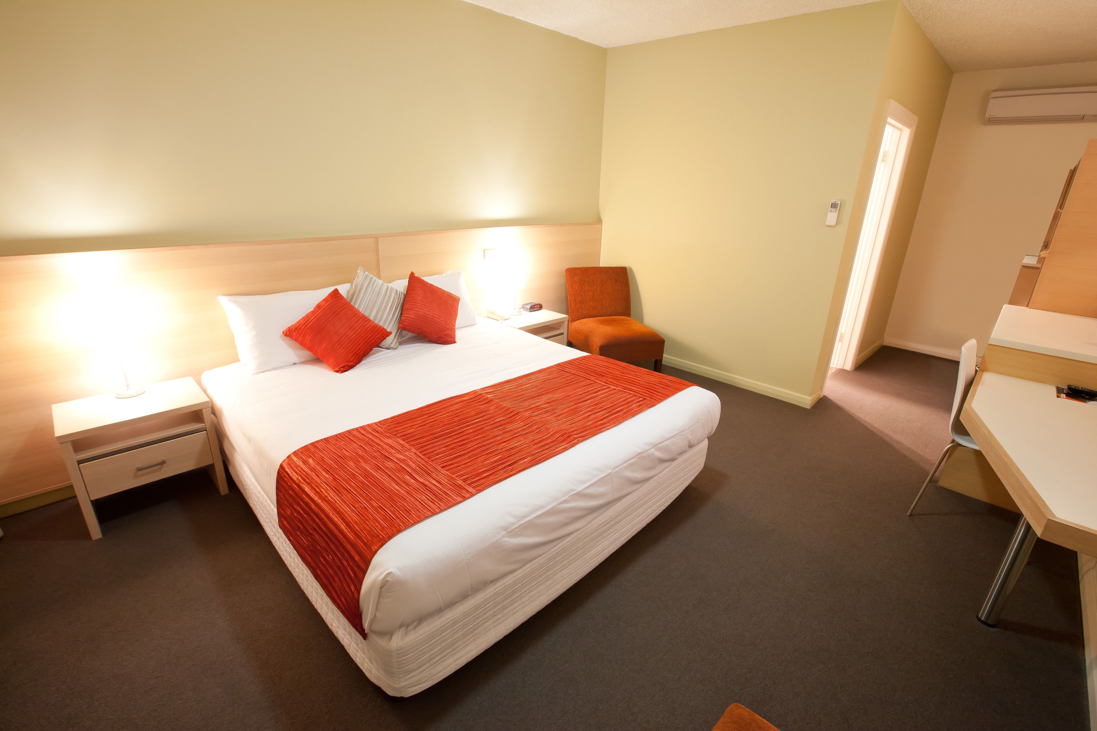 A hotel room with a large bed, a desk, and a chair.
