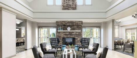 A spacious living room with a stone fireplace, comfortable seating, and large windows.