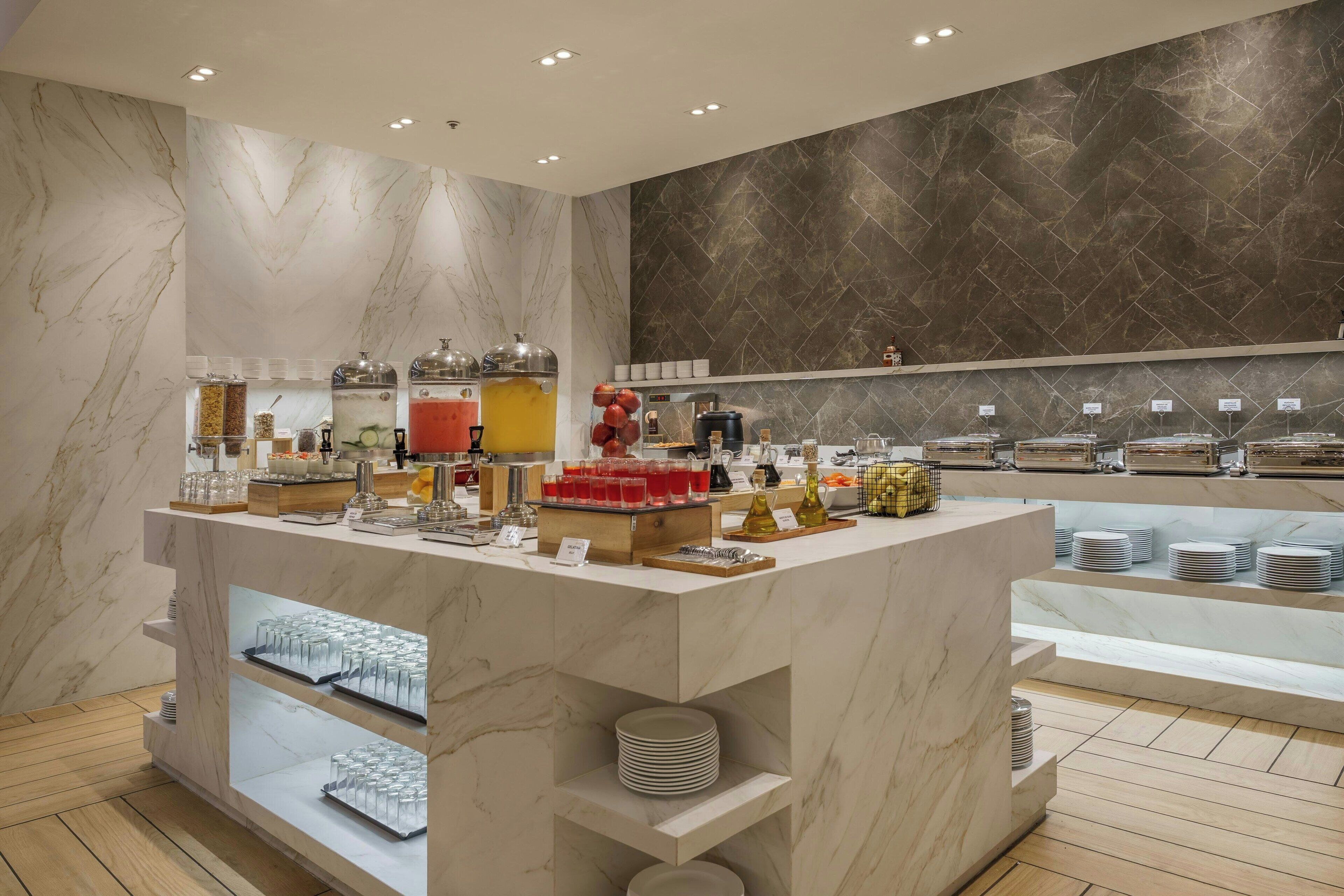 Un buffet proposant une variété de plats et de boissons, des murs en marbre et un design moderne.