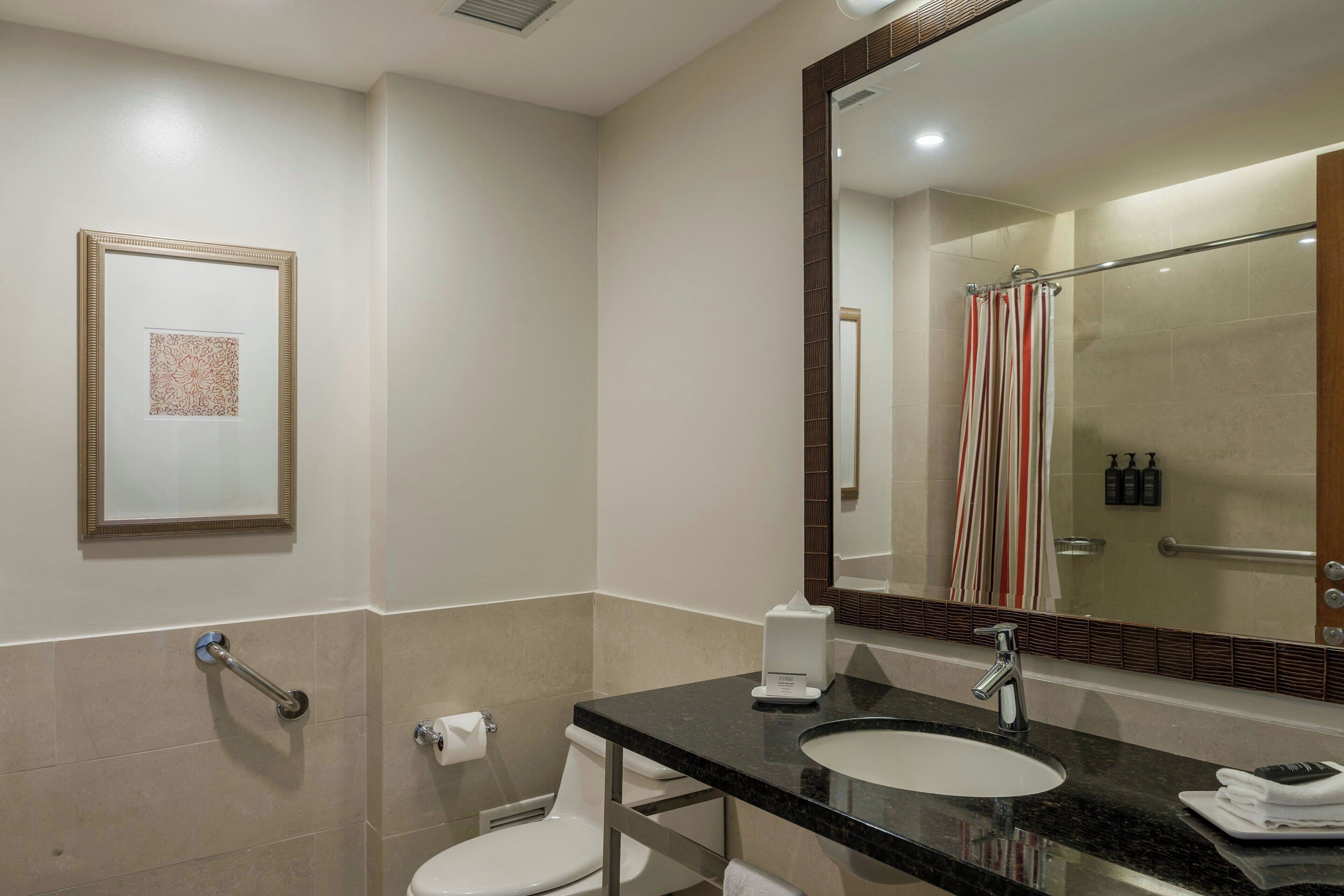 Une salle de bain moderne avec un grand miroir, un lavabo et des toilettes.