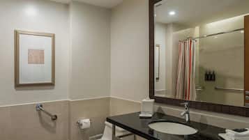 A modern bathroom with a large mirror, a sink, and a toilet.