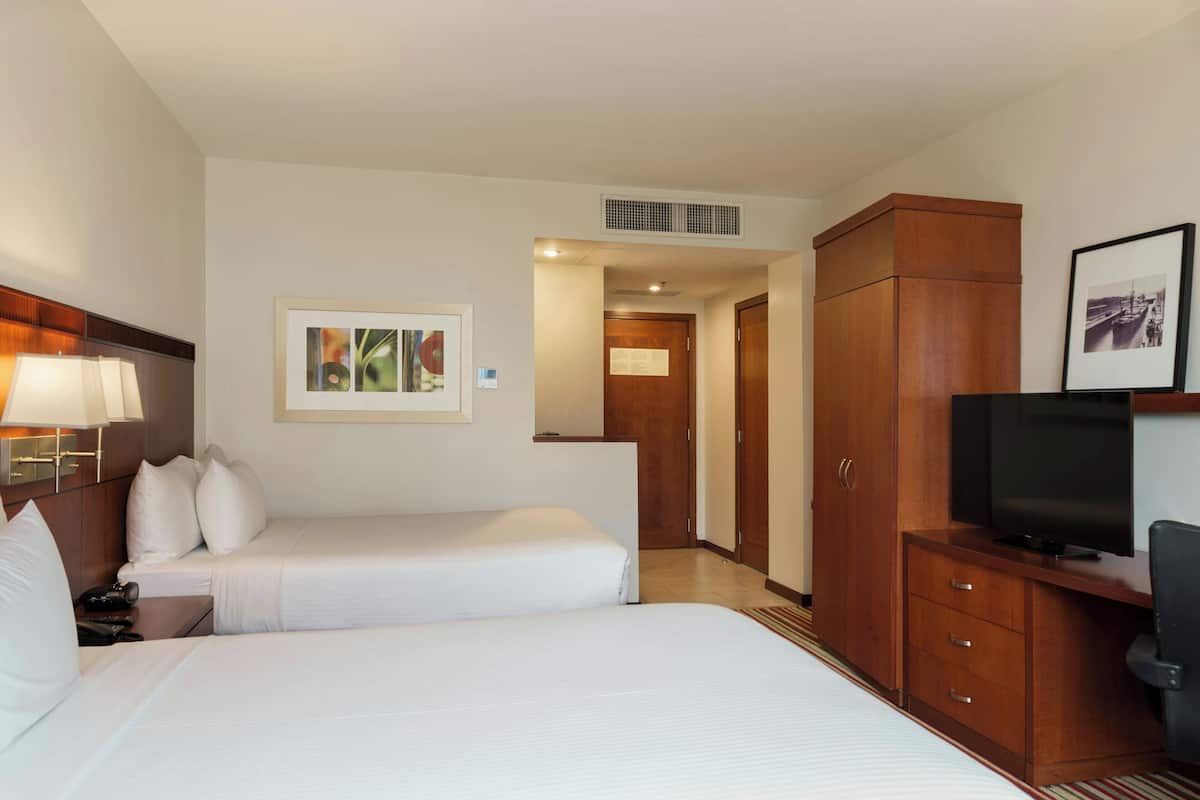 A hotel room with two beds, a TV, a desk, and a wardrobe.