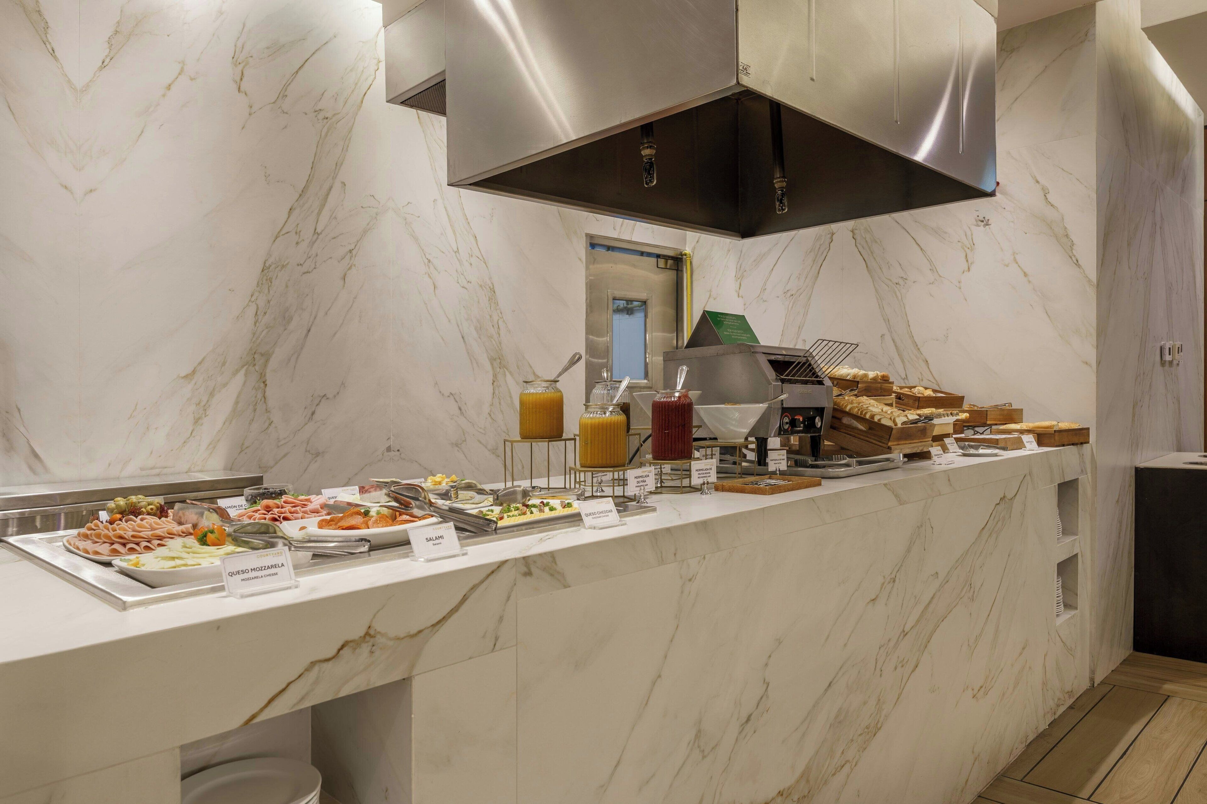 Un buffet proposant une variété de plats et une cuisine moderne dotée de plans de travail en marbre et d’appareils électroménagers en acier inoxydable.