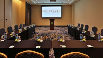 A conference room with a long table, chairs, and a screen displaying "COURTYARD BY MARRIOTT".