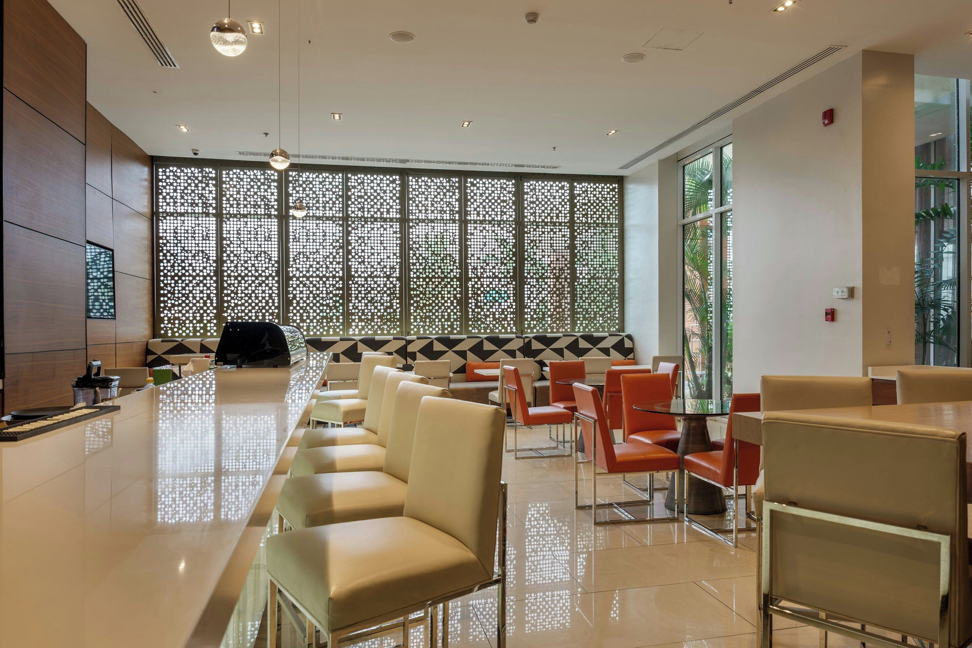 Eine moderne Hotellobby mit einer langen Rezeption, mehreren Sitzbereichen mit Sesseln und einer großen Dekoration.