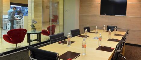 A conference room with a long table, chairs, and a TV screen on the wall.