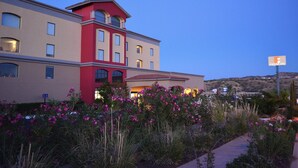A hotel with a red and beige facade, a landscaped garden with pink flowers, and a sign indicating it is a Fiesta Inn. - Fiesta Inn Nogales (Nogales)