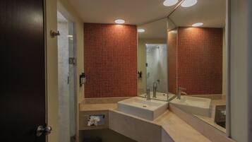 Un baño moderno con un espejo grande, dos lavamanos y paredes con azulejos rojos.