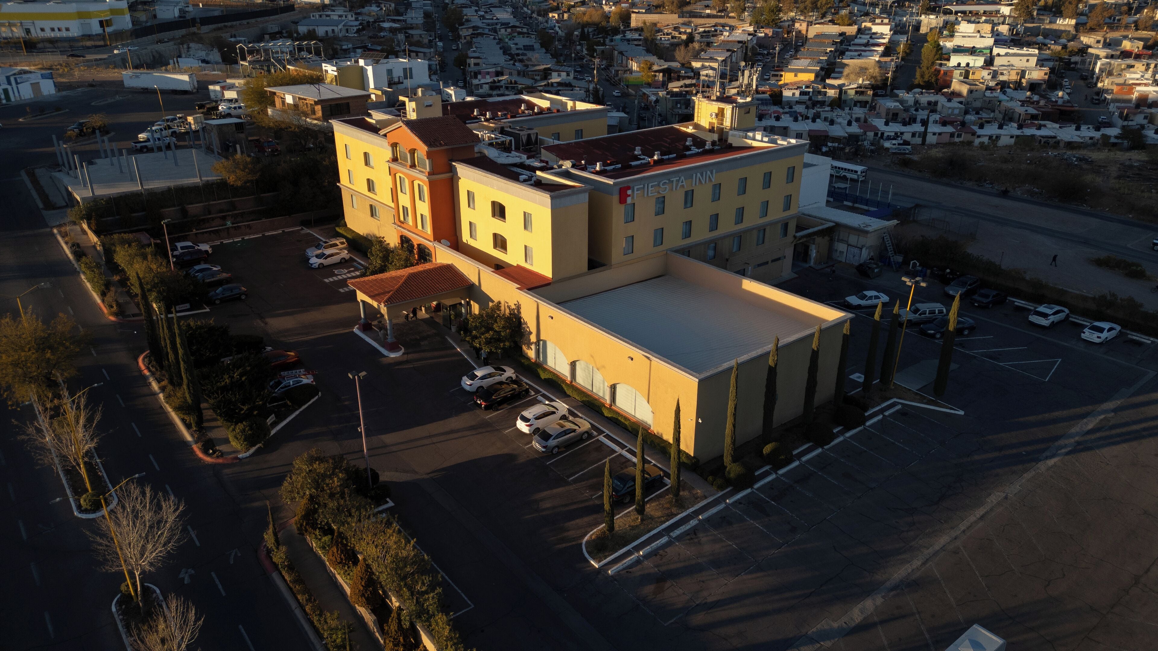 An aerial view of a multi-story building with a parking lot and a gas station.